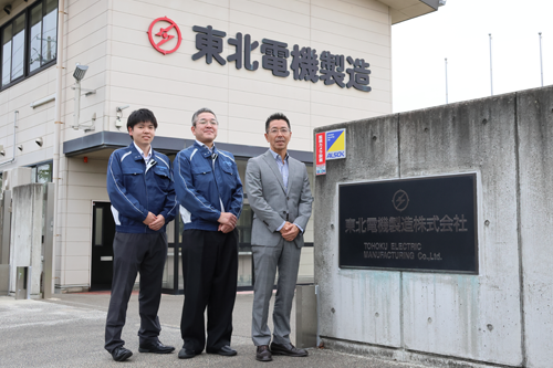 オフィスの前に笑顔で立つ東北電機製造株式会社の社員の方々